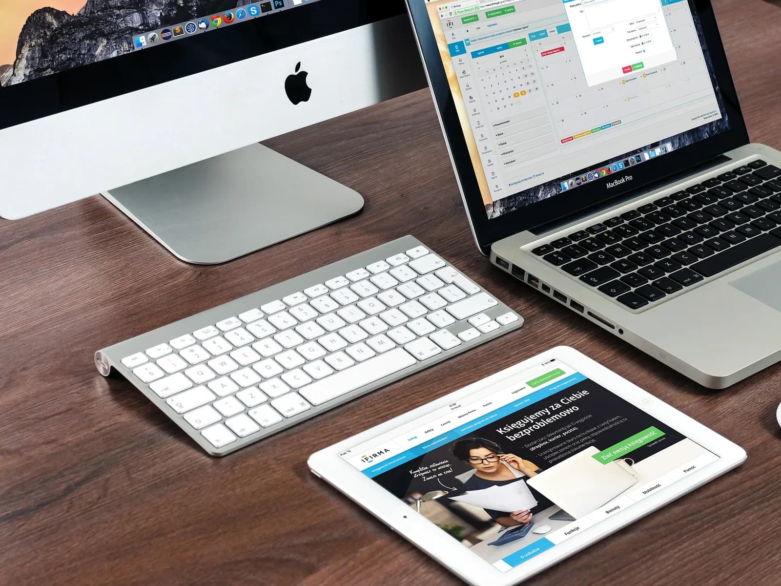 A desk with a desktop computer, a laptop and a tablet